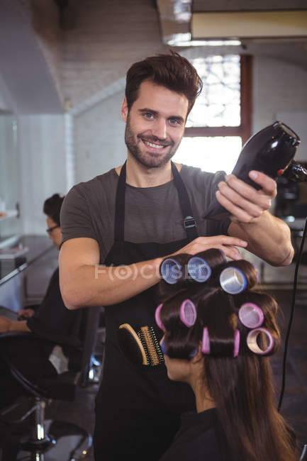 Sorrindo cabeleireiro masculino styling cabelo do cliente no salão — Fotografia de Stock