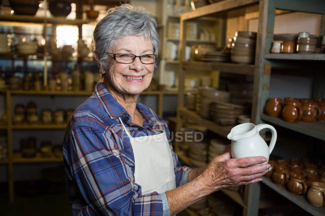 Портрет женщины-гончара с кувшином в керамической мастерской — стоковое фото