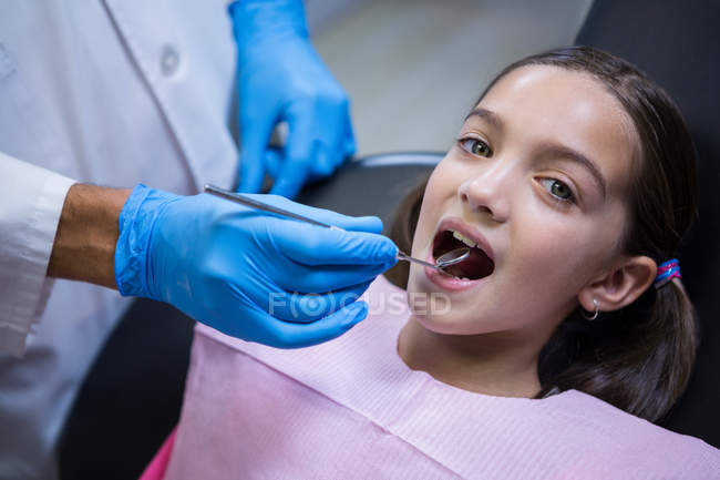 Odontoiatra che esamina giovane paziente con angolo specchio in clinica dentale — Foto stock