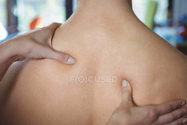 Image recadrée de physiothérapeute féminine donnant massage dos au patient masculin en clinique — Photo de stock