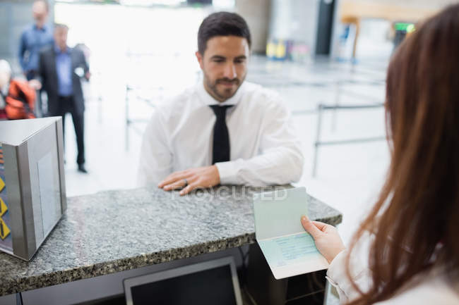 Airline check-in attendant checking passport of passenger at airport check-in counter — Stock Photo