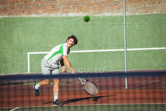 Homme jouant au tennis sur le terrain de sport en journée — Photo de stock
