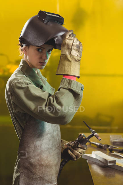 Soldador fêmea segurando tocha de soldagem na oficina — Fotografia de Stock