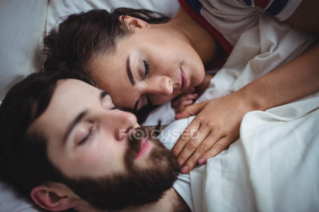 Pareja durmiendo juntos en la cama en el dormitorio - foto de stock