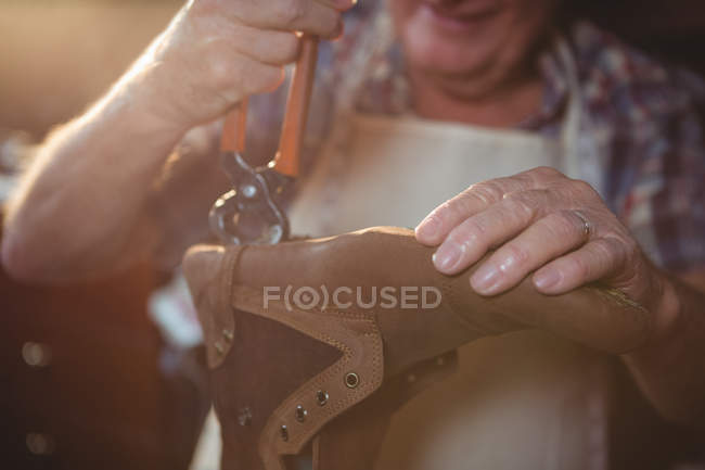 Mid section of shoemaker repairing a shoe in workshop — Stock Photo