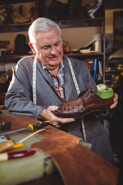 Fabricant de chaussures examinant une chaussure en atelier — Photo de stock