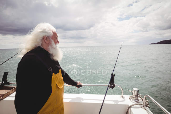Side view of Thoughtful fisherman standing on fishing boat — Stock Photo