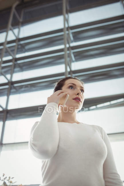Mujer hablando por teléfono móvil en la sala de espera en la terminal del aeropuerto - foto de stock