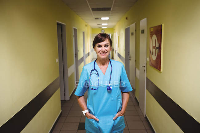 Портрет медсестри, що стоїть руками в кишені в лікарняному коридорі — стокове фото