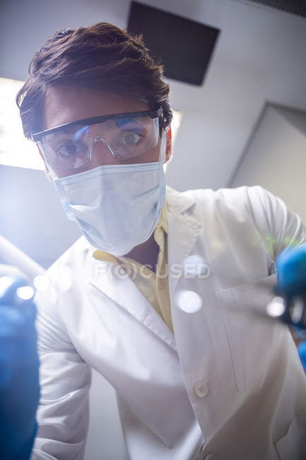 Dentist in surgical mask and protective glasses holding dental tools in dental clinic — Stock Photo
