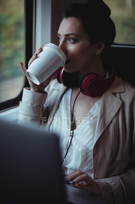 Jovem mulher bebendo café pela janela no trem — Fotografia de Stock