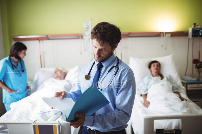 Arzt überprüft Bericht auf Krankenhausstation — Stockfoto