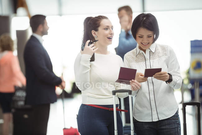 Dos mujeres revisando sus pasaportes en la terminal del aeropuerto — Stock Photo