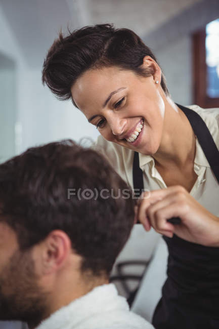 Hairdresser trimming client hair at hair salon — Stock Photo