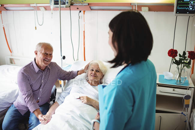 Pareja mayor interactuando con enfermera en el hospital - foto de stock
