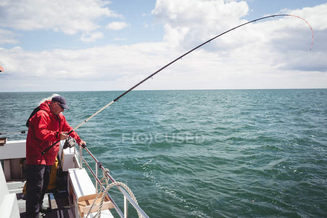 Pescador pesca com vara de pesca de barco — Fotografia de Stock
