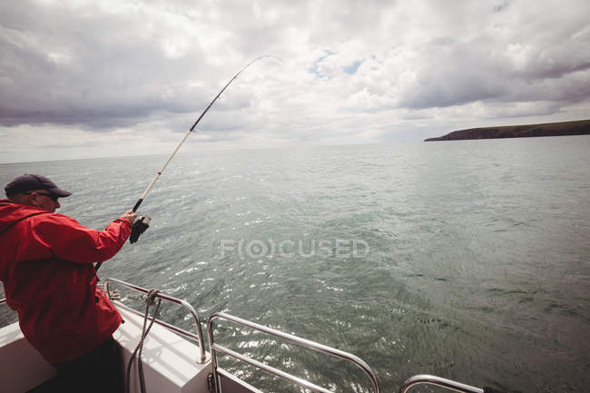 Pesca del pescador con caña de pescar del barco - foto de stock