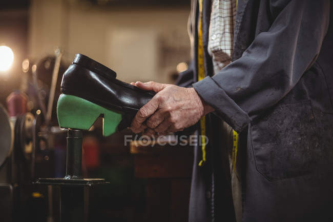 Mid section of male shoemaker repairing a shoe in workshop — Stock Photo