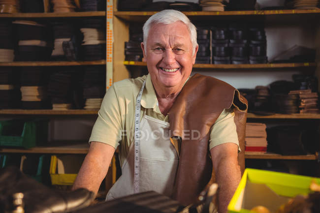 Portrait of smiling shoemaker sitting in workshop — Stock Photo