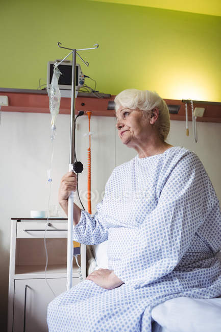 Nachdenkliche Seniorin sitzt im Krankenhaus auf Bett — Stockfoto