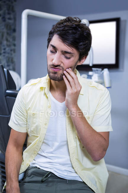 Несчастный человек, страдающий зубной болью в клинике — стоковое фото
