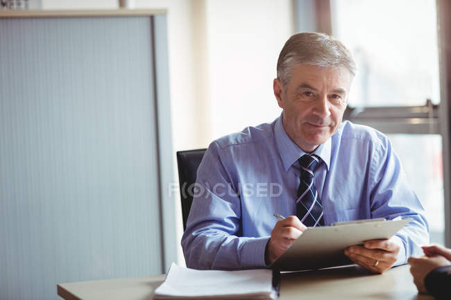 Retrato del hombre de negocios sosteniendo el portapapeles en el cargo - foto de stock