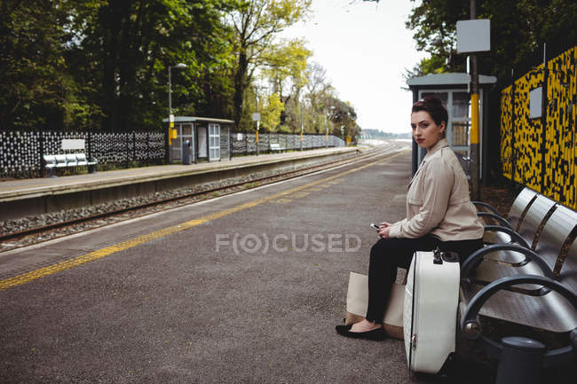 Hermosa mujer sentada en el banco en la plataforma de la estación de tren - foto de stock