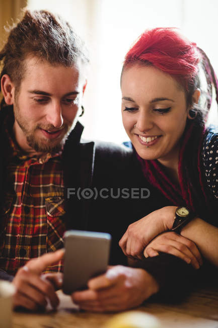Feliz pareja hipster utilizando el teléfono inteligente en casa - foto de stock