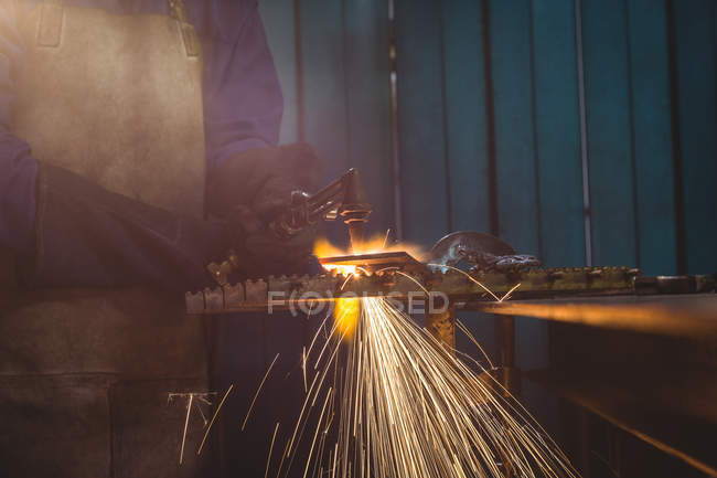 Обрезанное изображение женщины-сварщика, работающей на куске металла в мастерской — стоковое фото
