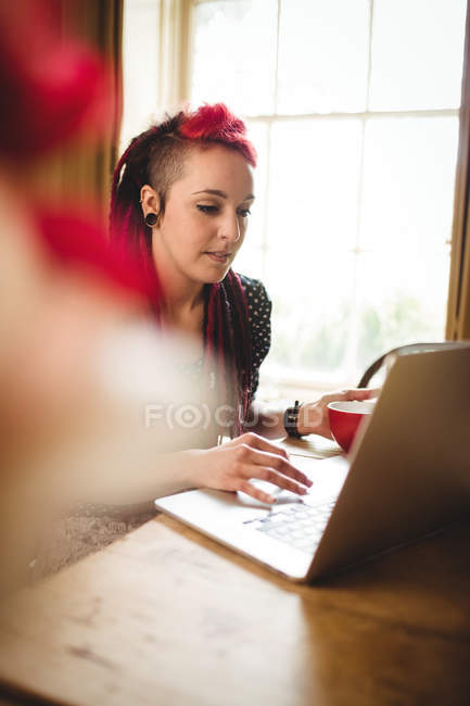 Красива жінка використовує ноутбук, сидячи вдома — стокове фото