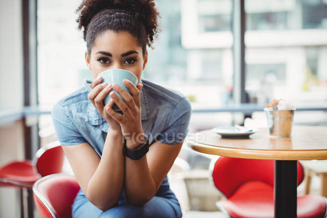 Портрет молодой женщины, пьющей кофе в ресторане — стоковое фото