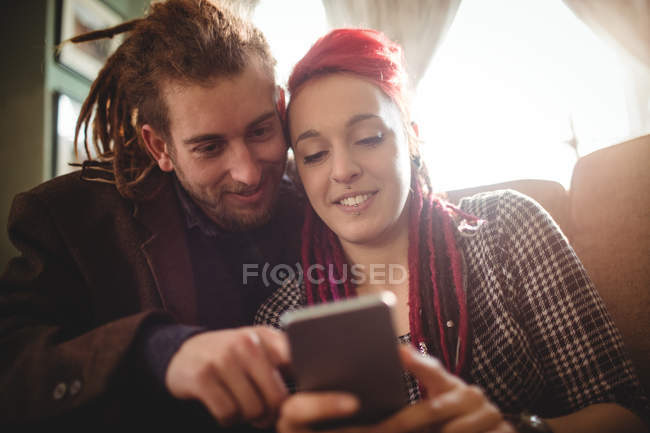 Feliz pareja hipster utilizando el teléfono móvil en casa - foto de stock