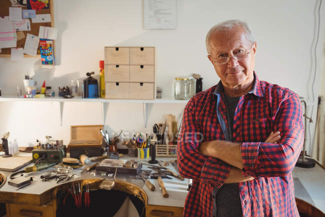 Portrait of goldsmith standing with arms crossed in workshop — Stock Photo