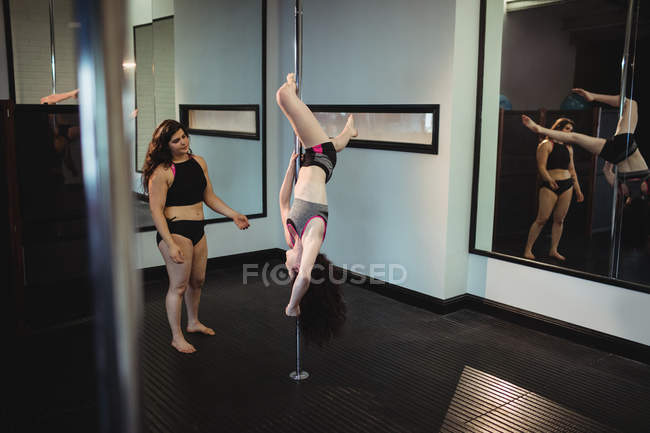 Instructor que ayuda a la bailarina de polo con la pose correcta en el gimnasio - foto de stock