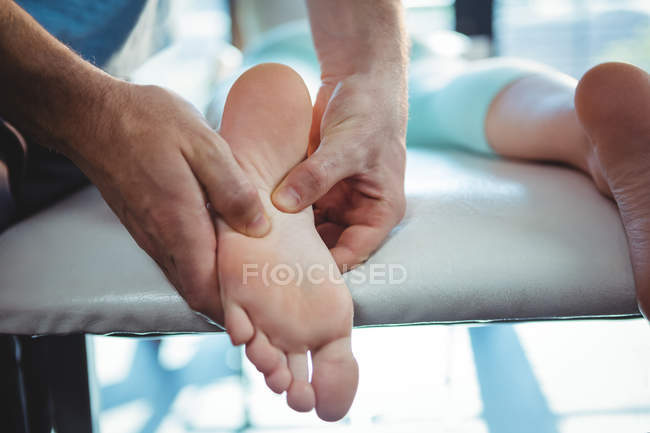 Обітнутого зображення чоловічого фізіотерапевт, даючи масаж ступень пацієнтки в клініці — стокове фото