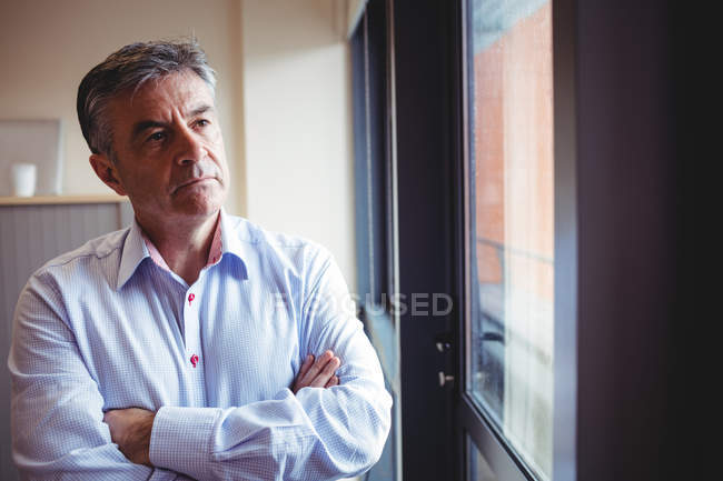 Close-up of doctor with arms crossed standing near window in hospital — Stock Photo