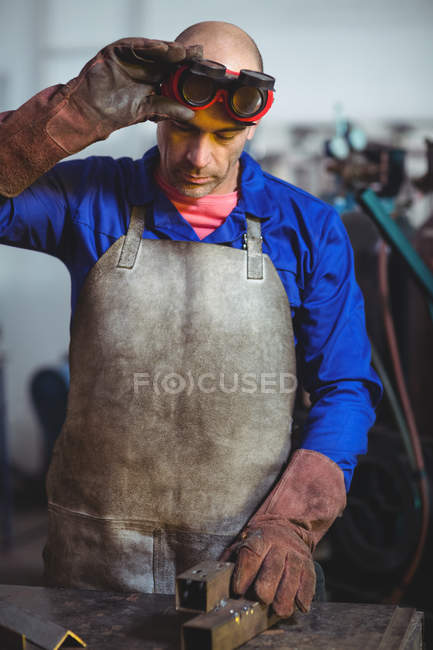 Male welder examining piece of metal in workshop — Stock Photo