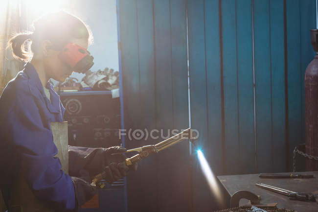 Soudeur femelle tenant la torche de soudage en atelier — Photo de stock