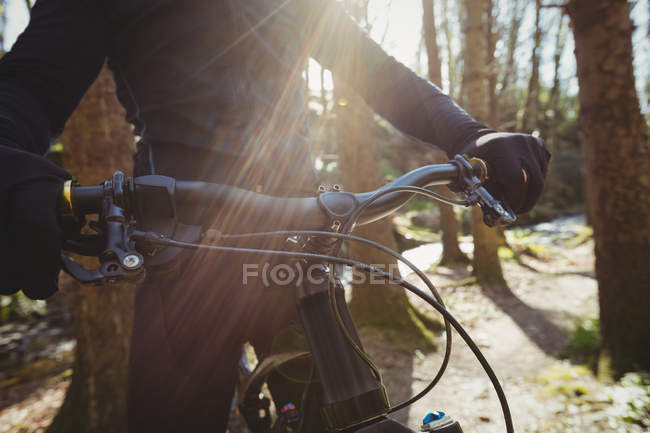 Sección media del ciclista de montaña que monta en el bosque - foto de stock