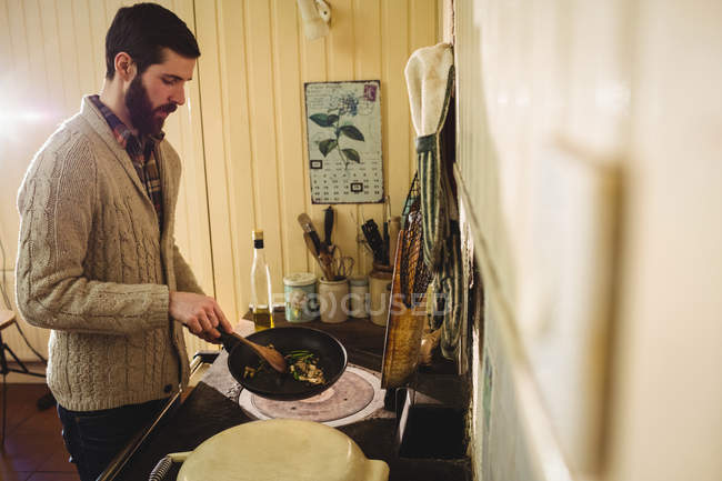 Uomo che prepara il cibo in cucina a casa — Foto stock