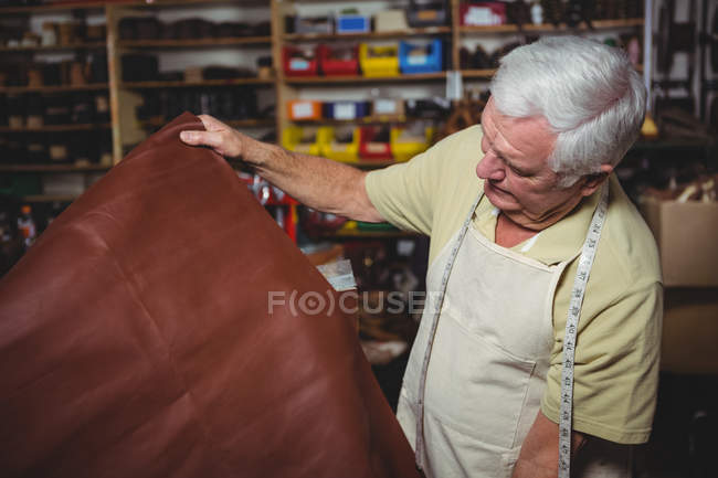Shoemaker examining a piece of leather in workshop — Stock Photo