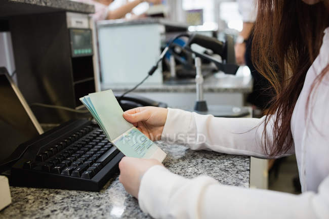Assistente de check-in da companhia aérea que verifica o passaporte do passageiro no balcão de check-in do aeroporto — Fotografia de Stock