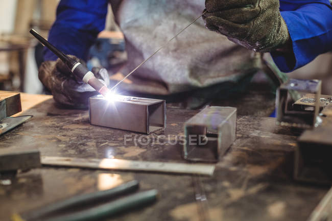 Кадроване зображення чоловічого зварювальник, працюючи на шматок металу в майстерні — стокове фото