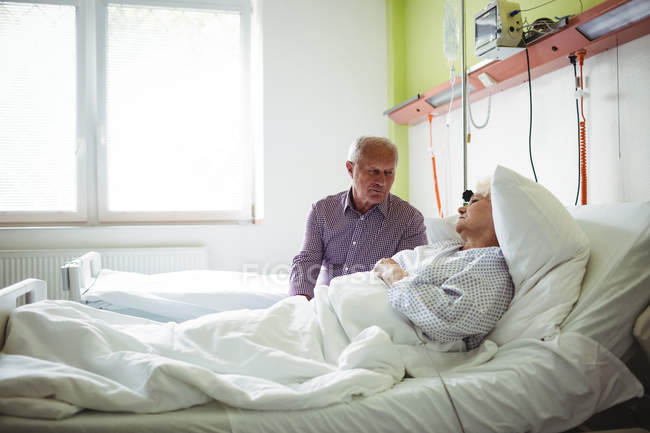 Homem sênior consolando mulher idosa no hospital — Fotografia de Stock