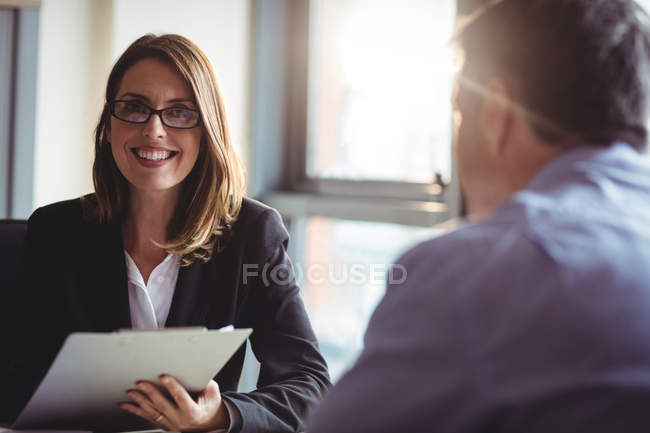 Portrait of businesswoman holding clipboard in office — Stock Photo