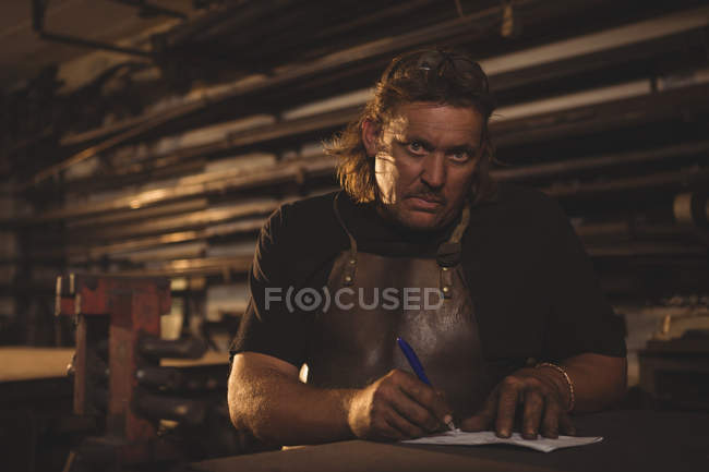 Retrato del herrero preparando notas en el taller - foto de stock