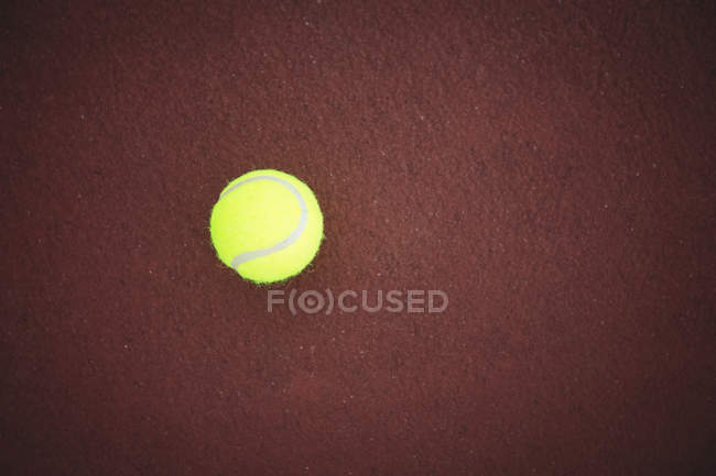 Теннисный мяч на коричневой земле на спортивной площадке — стоковое фото