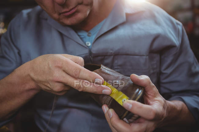 Shoemaker measuring a shoe with measure tape in workshop — Stock Photo