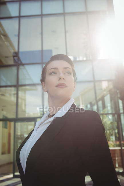 Selbstbewusste Geschäftsfrau steht an einem sonnigen Tag vor einem Bürogebäude — Stockfoto