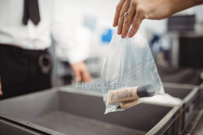 Pasajero poniendo bolsa de plástico en bandeja para control de seguridad en el aeropuerto - foto de stock